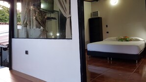 Une chambre à coucher avec un lit, une fenêtre avec des rideaux, un ventilateur de plafond et un climatiseur fixé au mur.