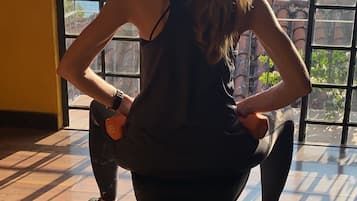 A person performing a squat exercise on a bench in a room with large windows overlooking a body of water and mountains.