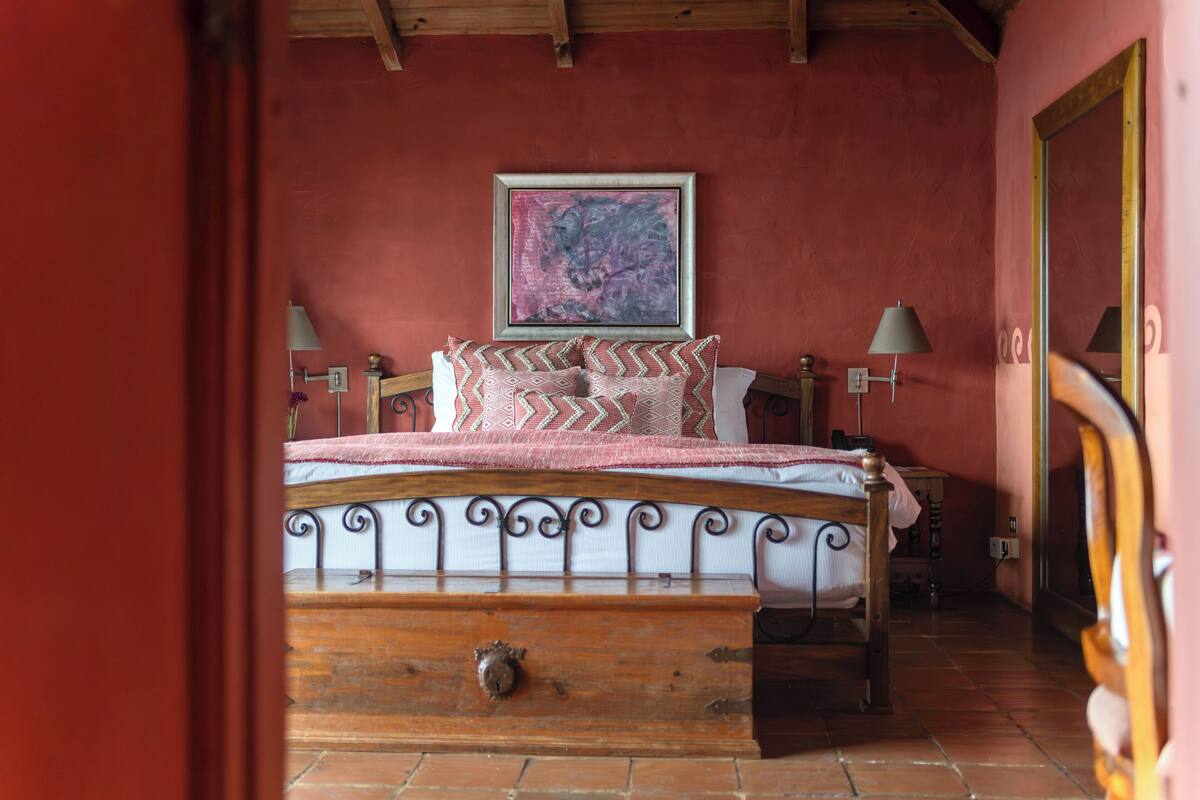 Une chambre à coucher avec un lit en bois, un tableau au mur et une lampe de chaque côté du lit.