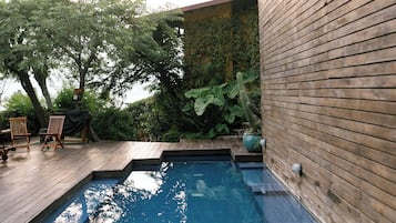 Una piscina al aire libre, sillones reclinables de piscina