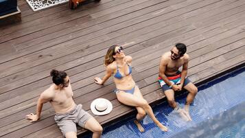A wooden deck with lounge chairs and a pool.