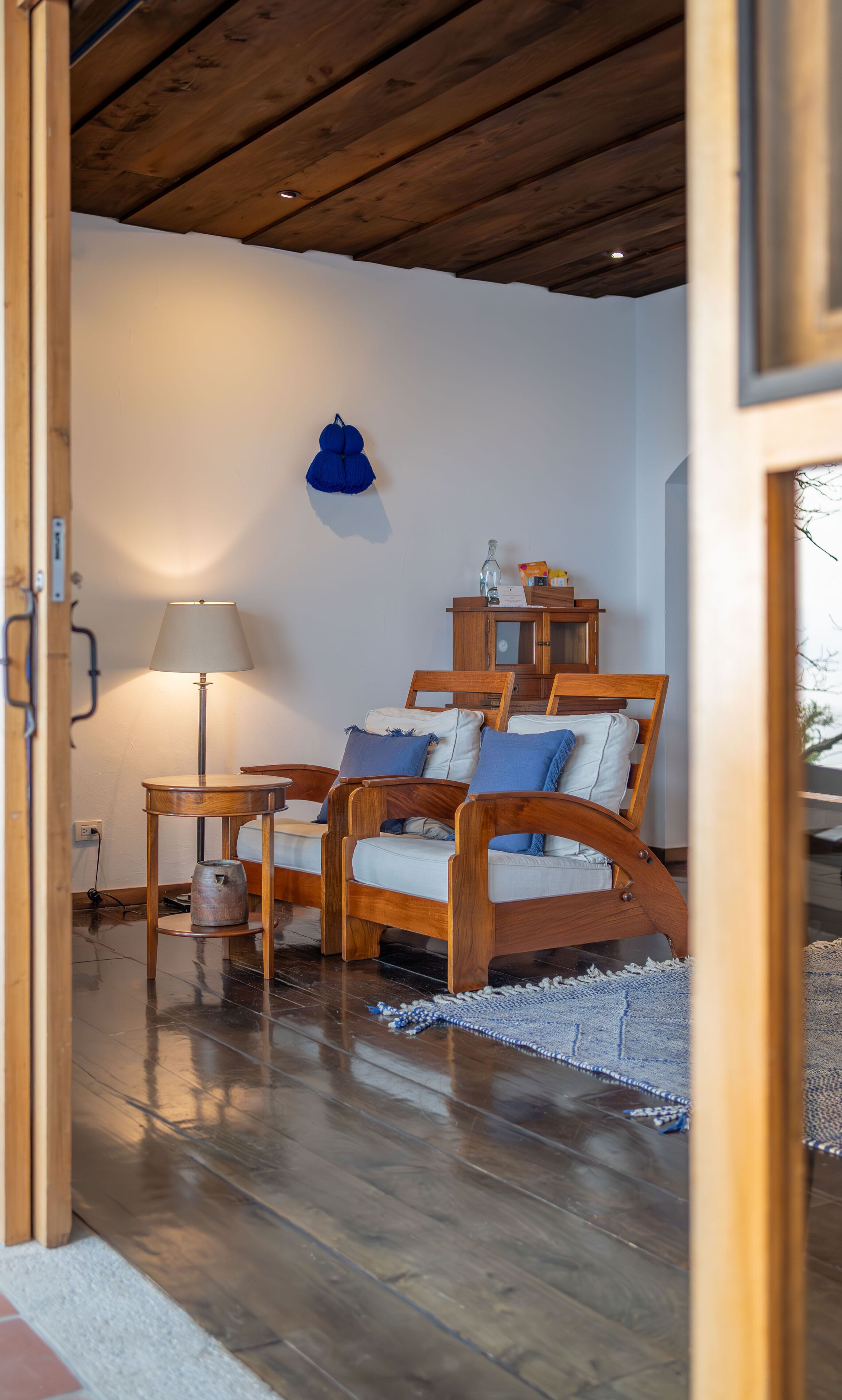Ein gemütliches Zimmer mit Holzboden, einem Bett mit blauer Bettwäsche, einem Holzschrank und einer Lampe.