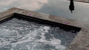 Une piscine à débordement offrant une vue sur une chaîne de montagnes et un plan d’eau.