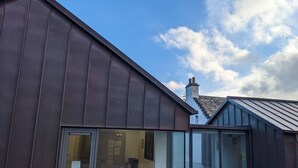 A modern building with large windows and a visible chimney. - Ferry Inn Stromness (Stromness)
