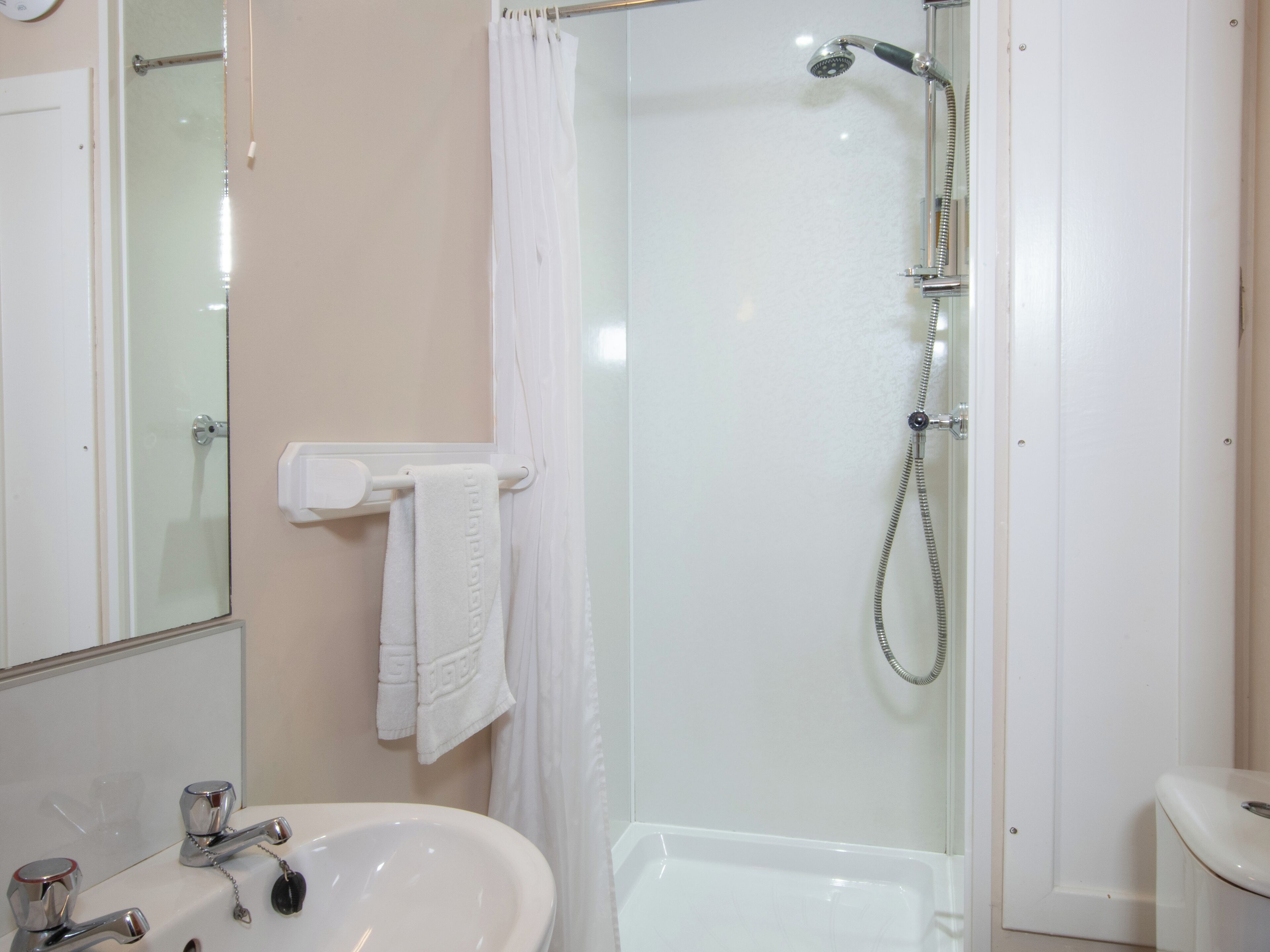 A bathroom with a glass-enclosed shower, a white sink, and a toilet.