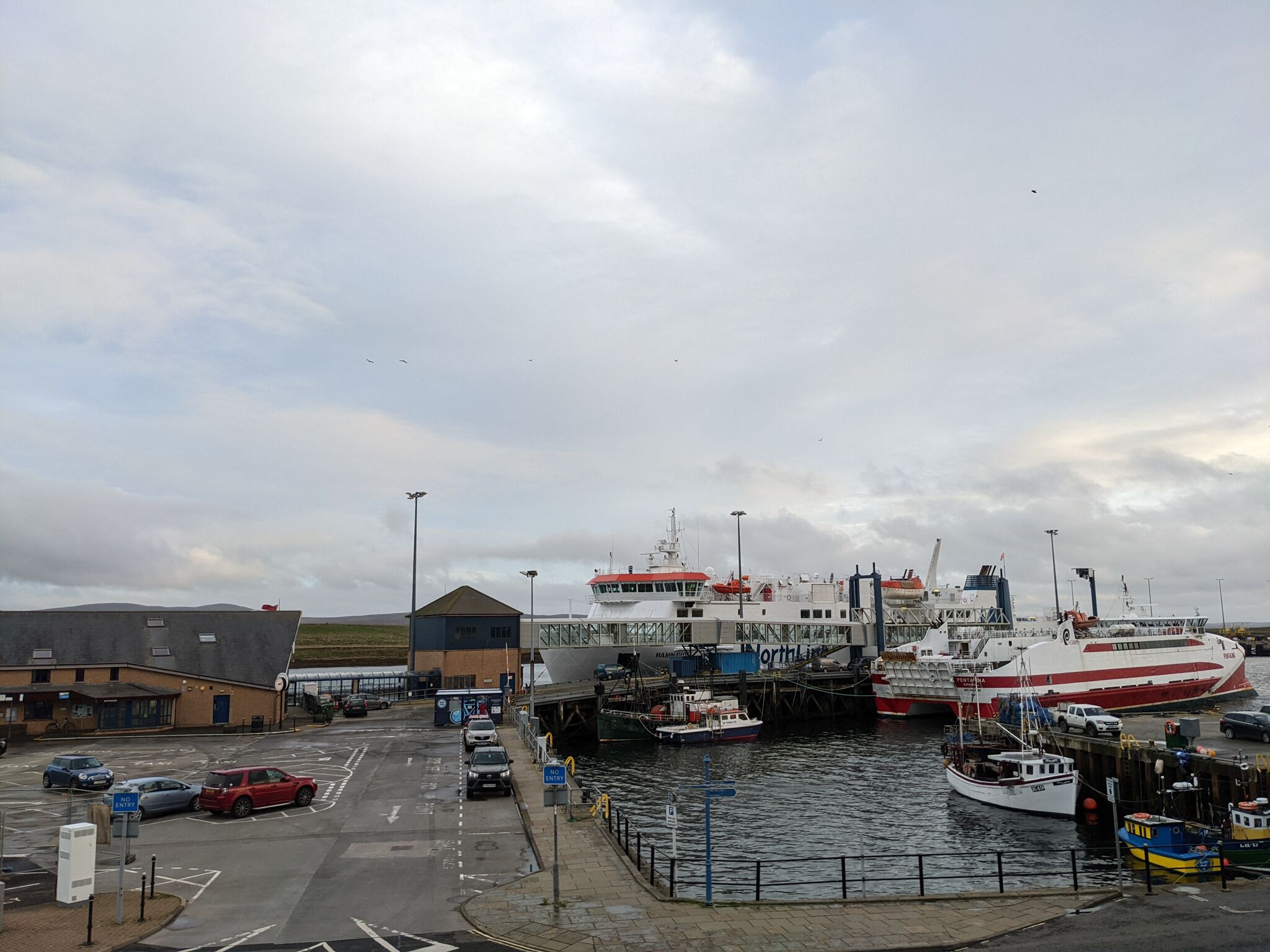 A harbor with boats docked, a building with a red roof, and a clear sky.