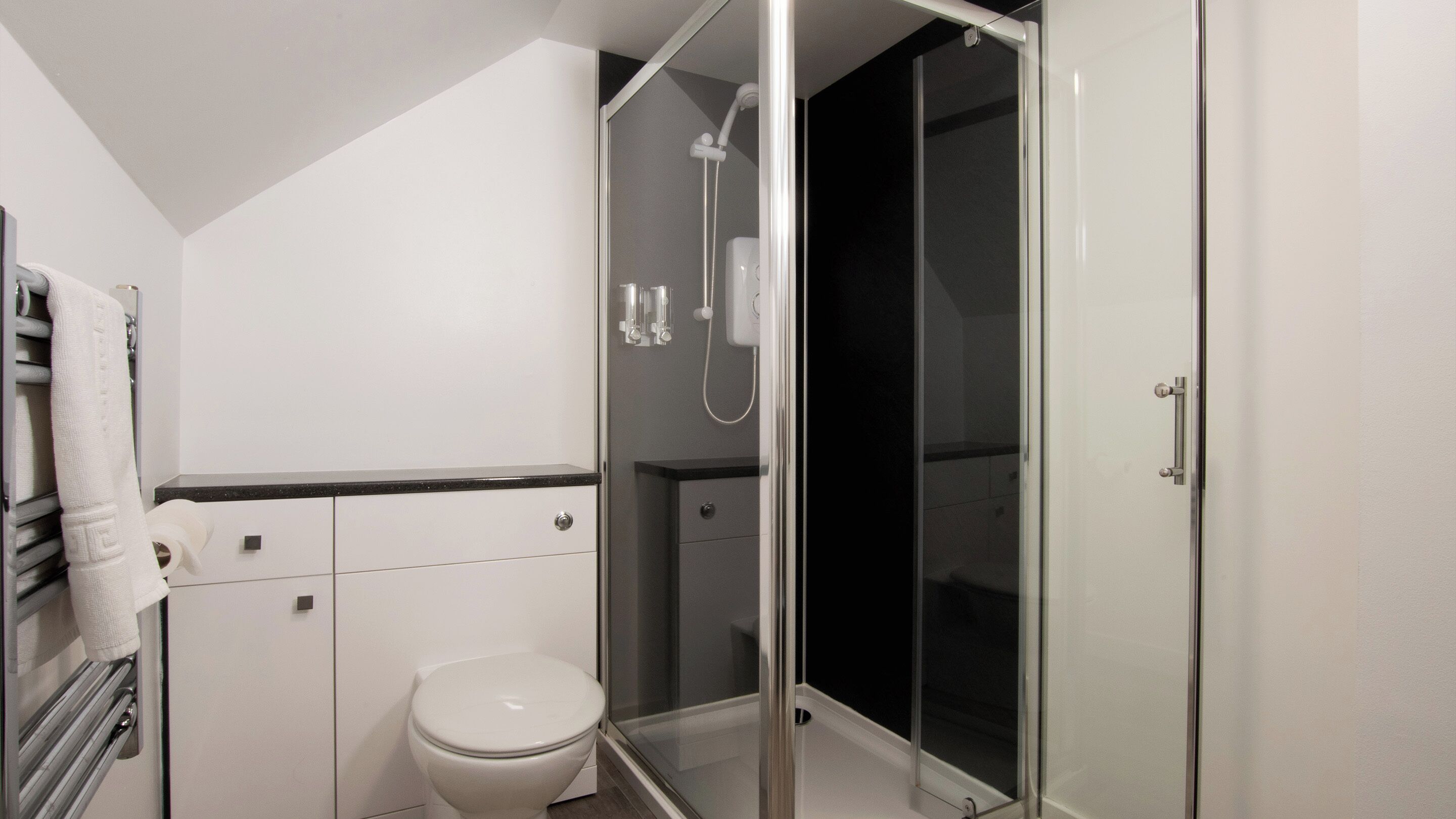 A modern bathroom with a toilet, a glass-enclosed shower, and a towel rack.