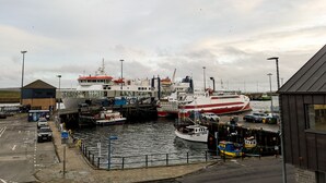A harbor with boats docked, a control tower, and a building with a red roof. - Ferry Inn Stromness (Stromness)