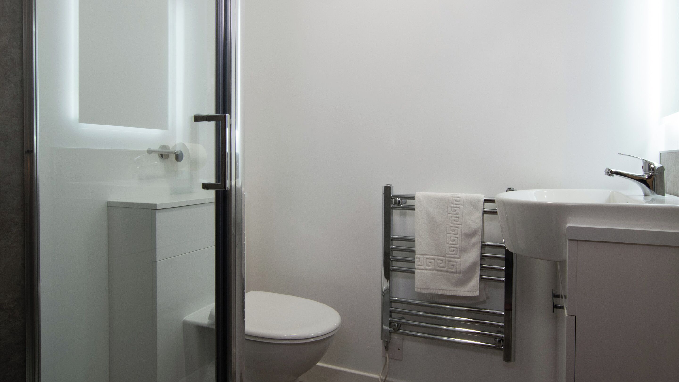 Une salle de bain comprenant des toilettes, un lavabo et une douche à parois de verre.
