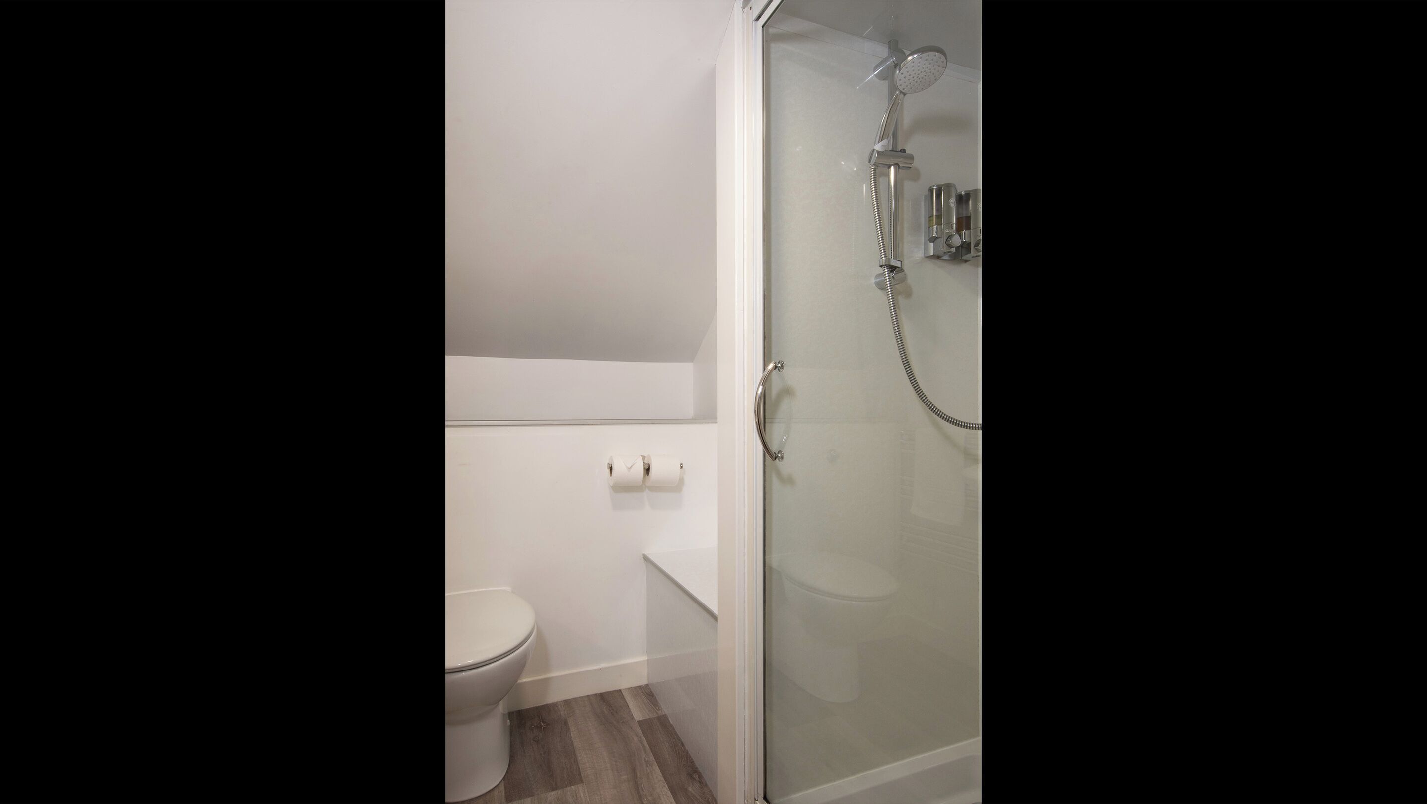Une salle de bain moderne avec une douche à parois de verre, des toilettes et un lavabo blanc.