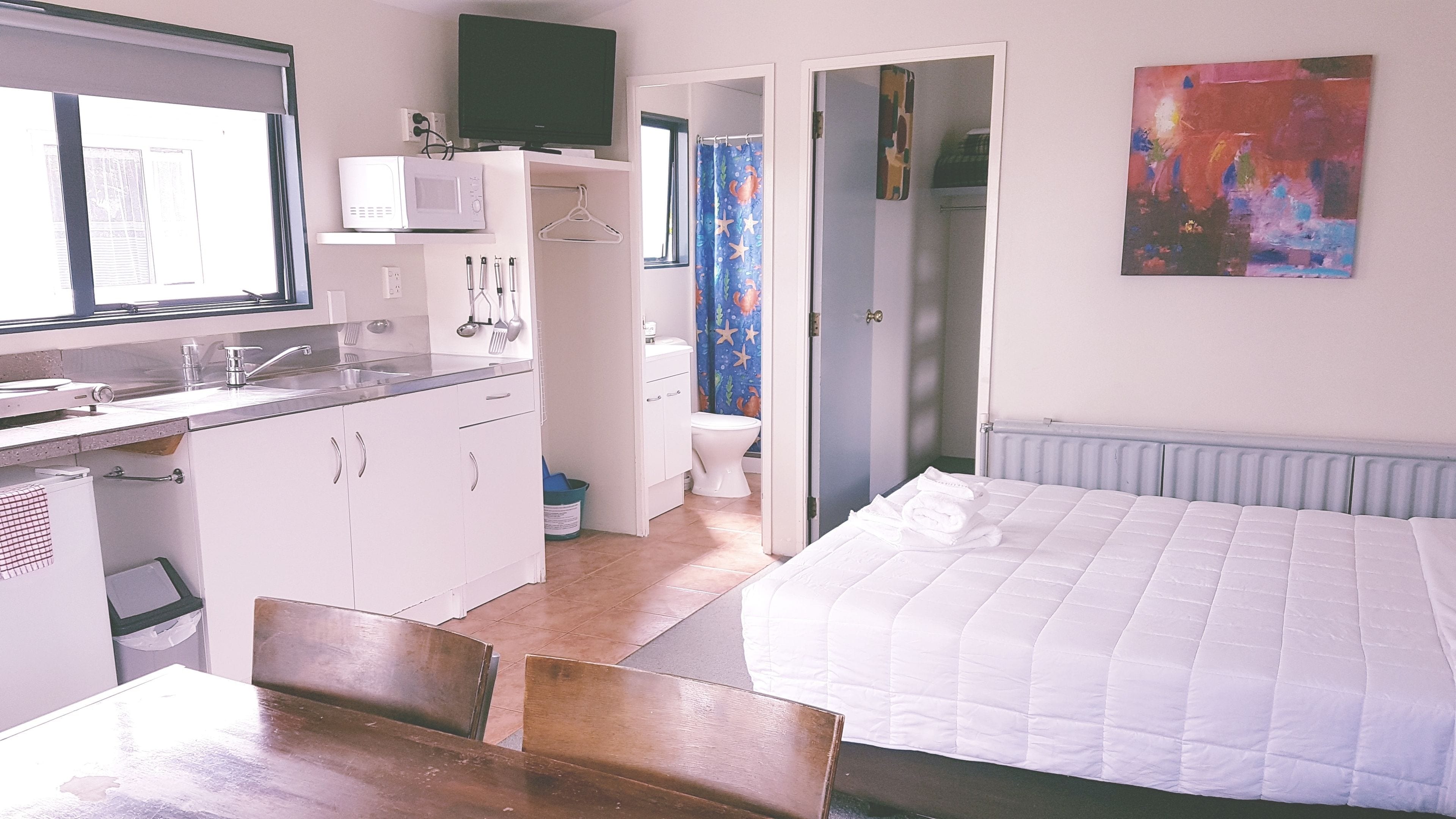 Una habitación pequeña con kitchenette, una cama y un baño.