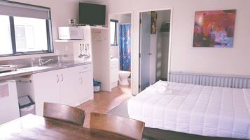Una habitación pequeña con kitchenette, una cama y un baño.