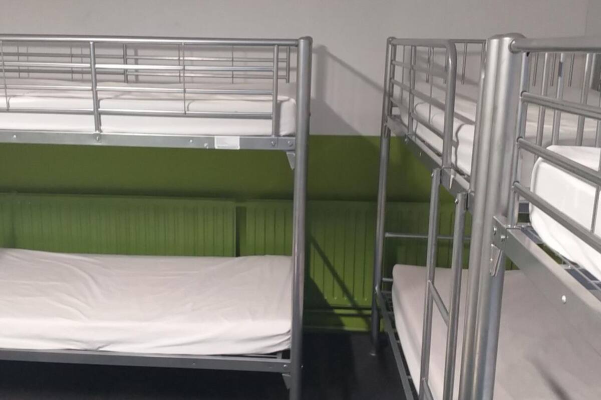 Stapelbedden met metalen spijlen en een groene wand.