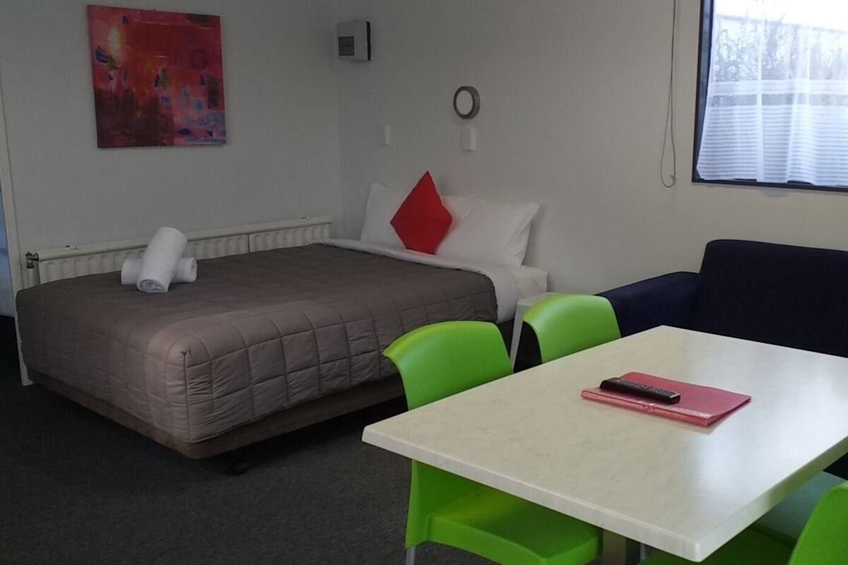 Een kamer met een bed, een klein tafeltje en twee stoelen.