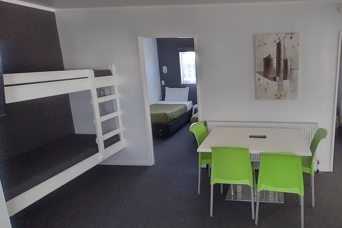 Een kamer met stapelbedden, een tafel met stoelen en een radiator.