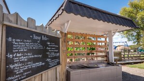Un stand de nourriture avec un tableau noir servant de menu, où sont indiqués des plats comme « le menu complet » et « les maïs doux ».