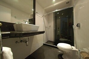 Une salle de bain moderne avec un lavabo blanc, une douche à parois de verre et des toilettes.