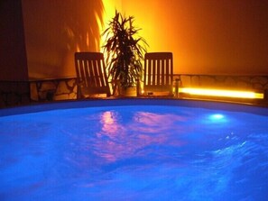 Une piscine avec deux chaises en bois et une plante en pot.
