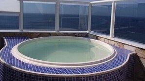 Un jacuzzi con vistas despejadas al océano a través de amplios ventanales.