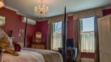 A bedroom with a bed, a dresser, a mirror, and a chandelier.