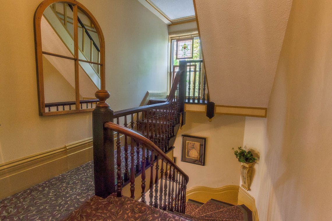 A staircase with wooden balusters and a patterned carpet.