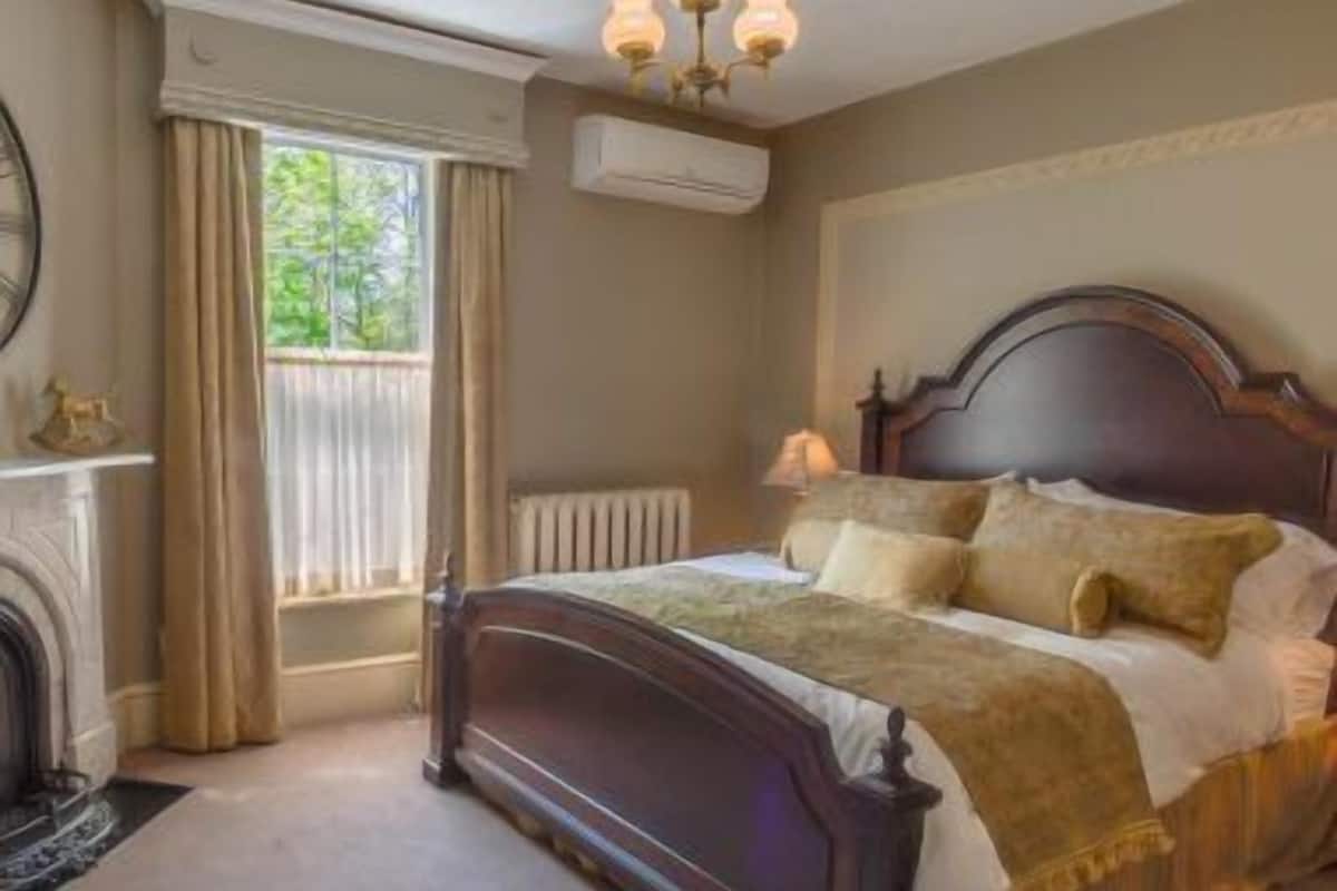 A bedroom with a large bed, a fireplace, and a window with curtains.