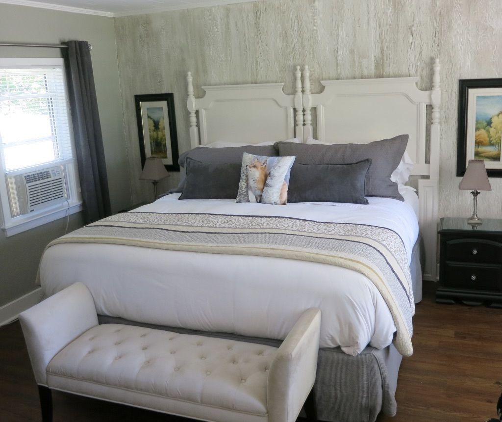 A bedroom with a large bed, a bench, a nightstand, and a lamp.