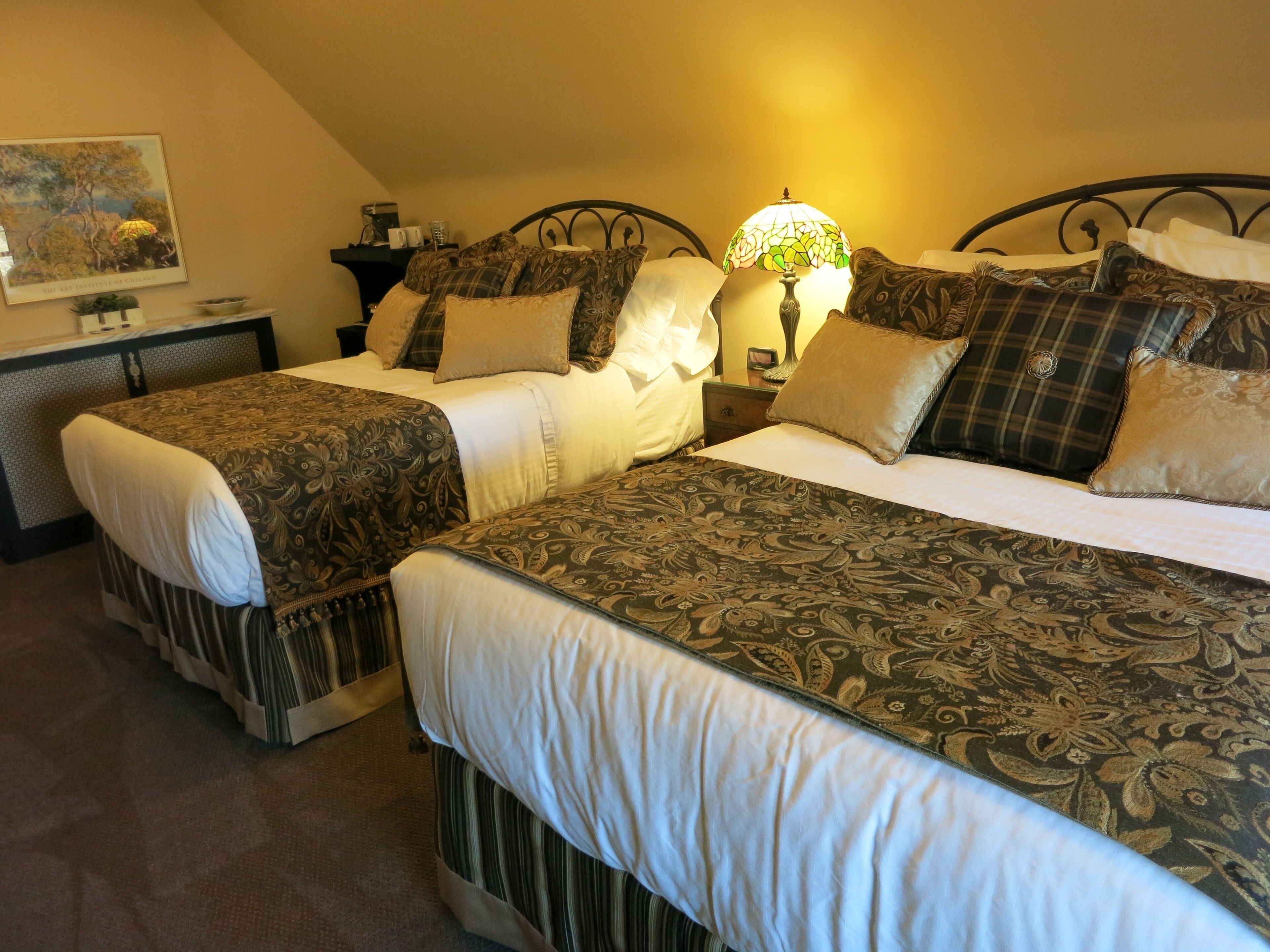 Een slaapkamer met twee bedden, elk voorzien van beddengoed met een patroon en een nachtkastje met een lamp.