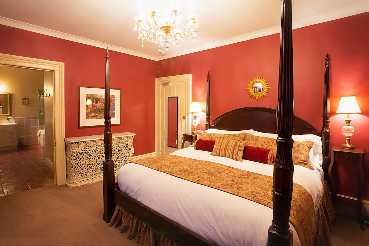 A four-poster bed with a canopy, a chandelier, and a sunburst wall decoration.