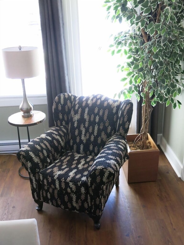 A room with a patterned armchair, a lamp, and a potted plant.