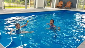 Una piscina interior con dos niños nadando.