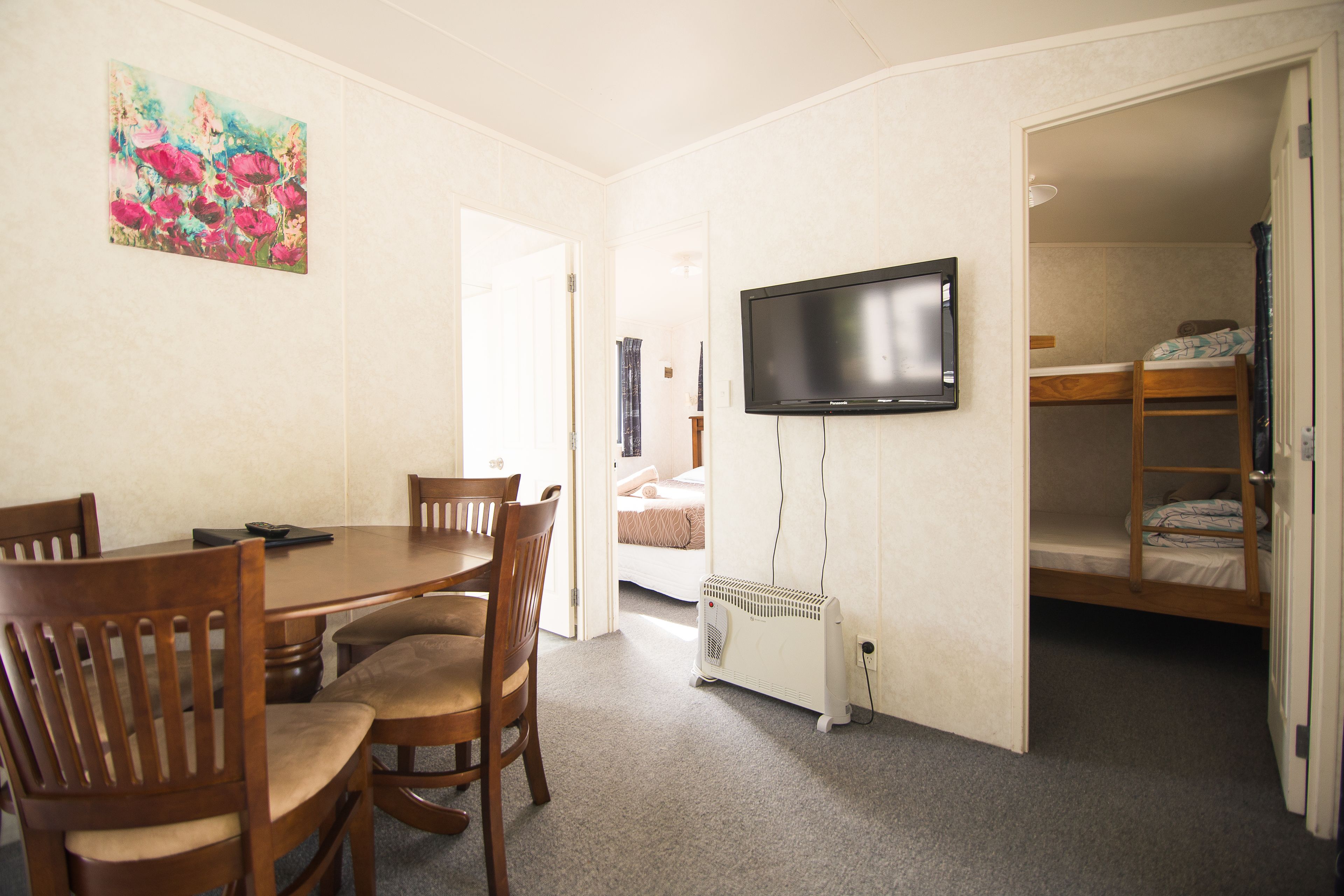 Ein Zimmer mit Esstisch, Stühlen, Fernseher und einem Etagenbett.