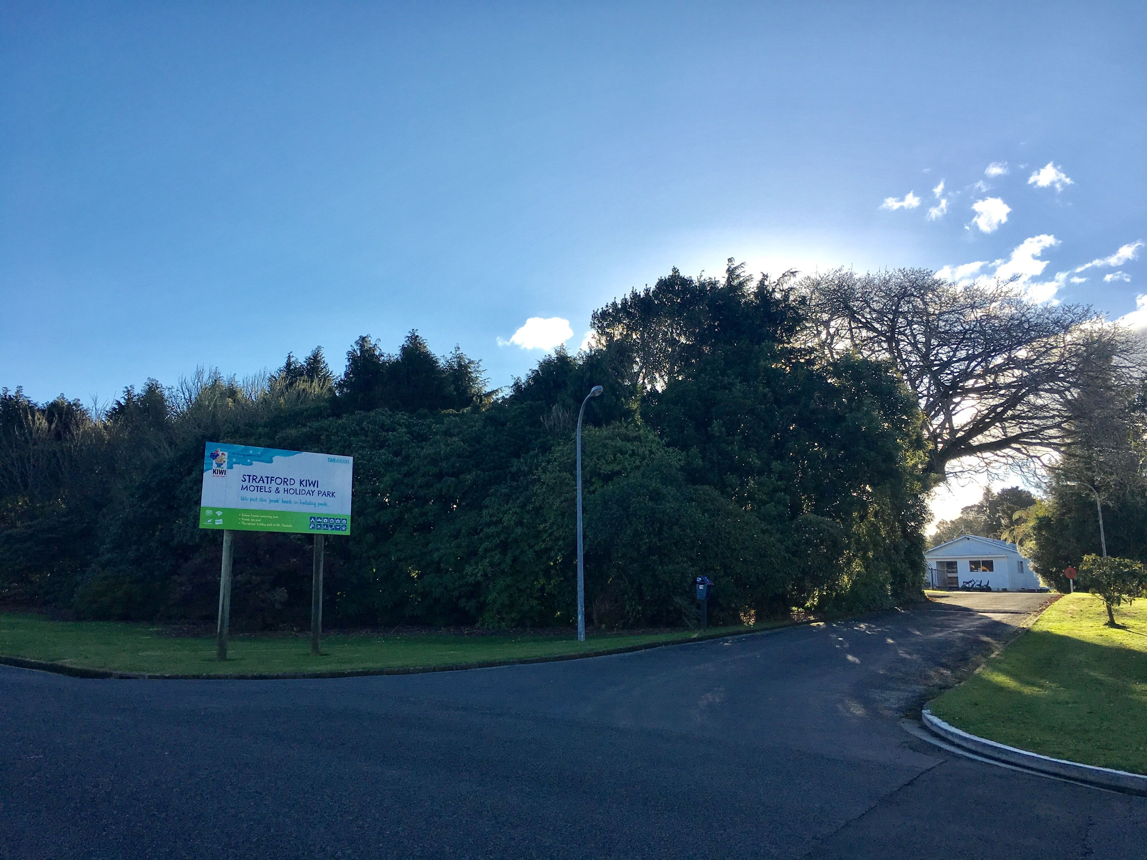 A road leading to a sign for Stratford Kiwi Motels & Holiday Park.