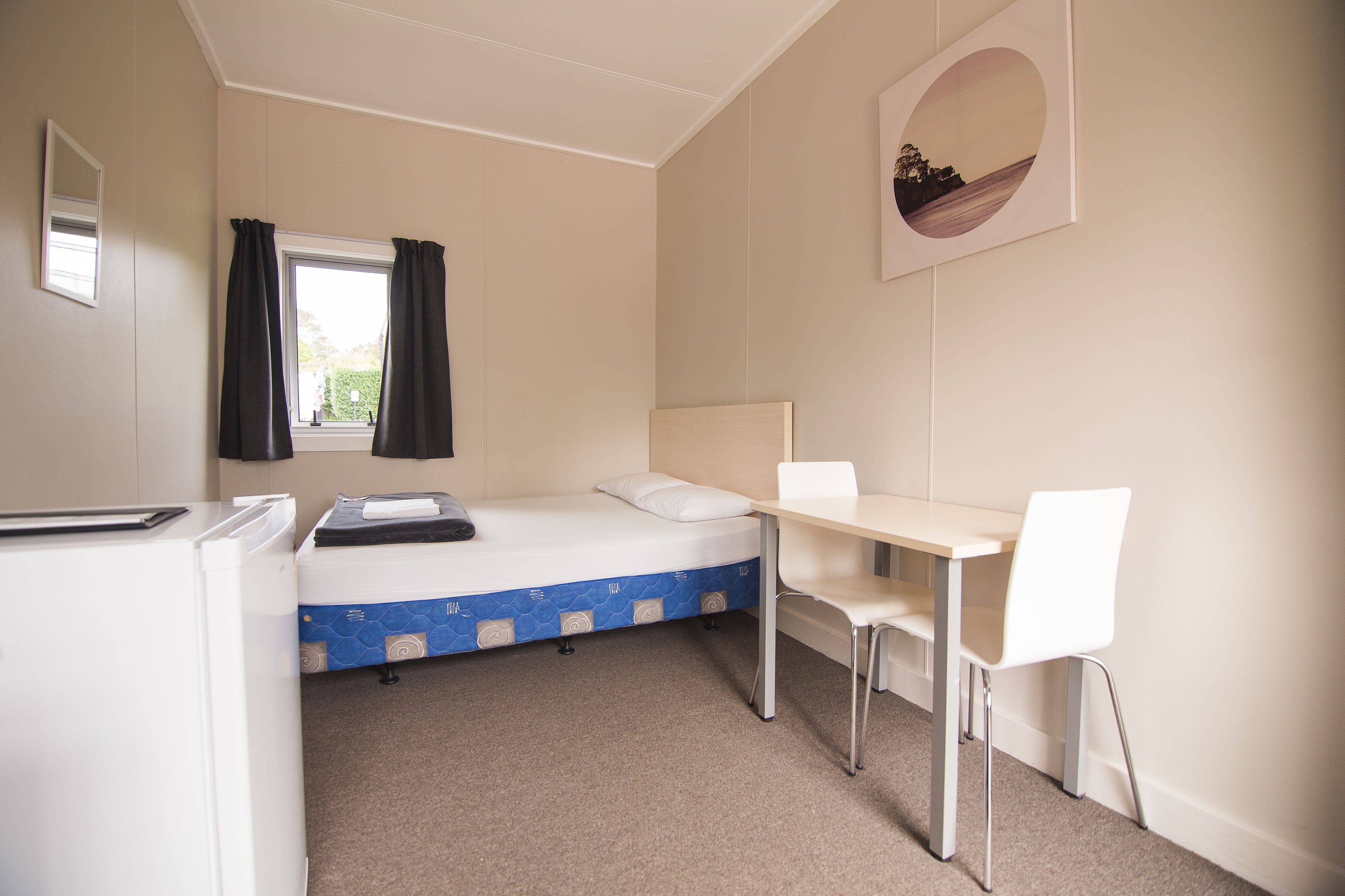 A compact room with a bed, a desk, and a chair.