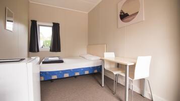 A compact room with a bed, a desk, and a chair.