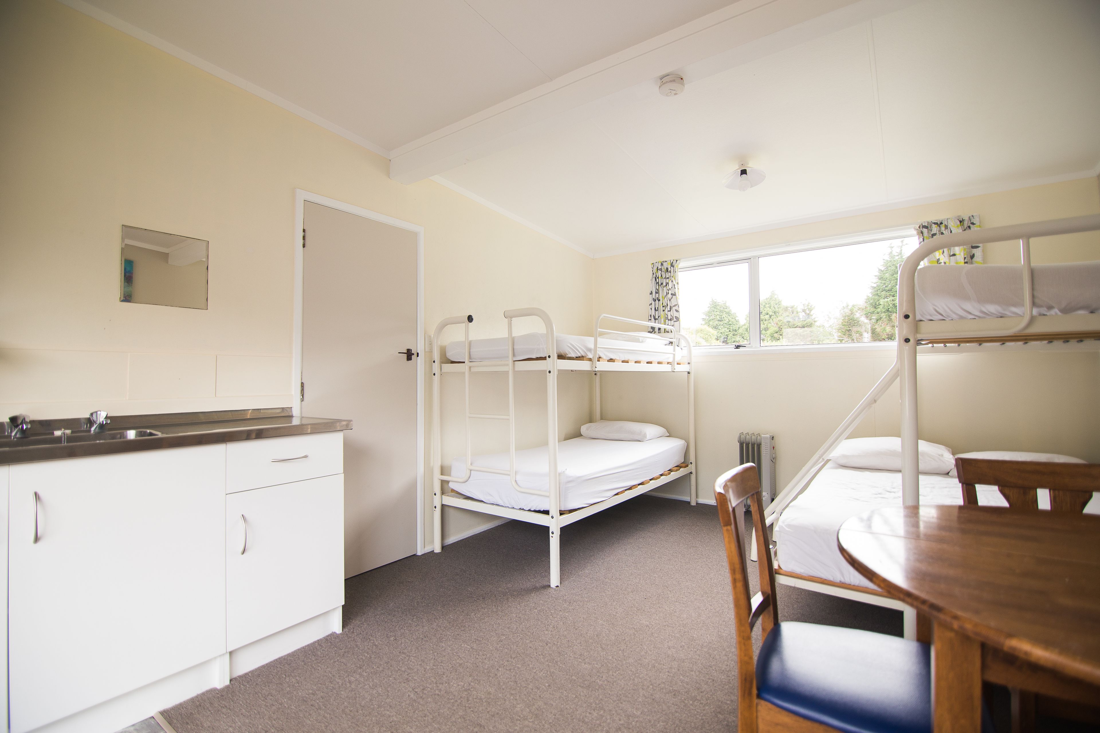 A room with bunk beds, a kitchen area, and a dining table.