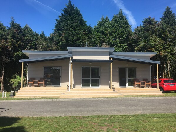 A modern building with a covered porch, large windows, and a red car parked nearby. - Stratford Motel & Holiday Park (Stratford)
