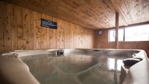Un spa de madera con un jacuzzi, un reloj y un cartel con instrucciones de seguridad.