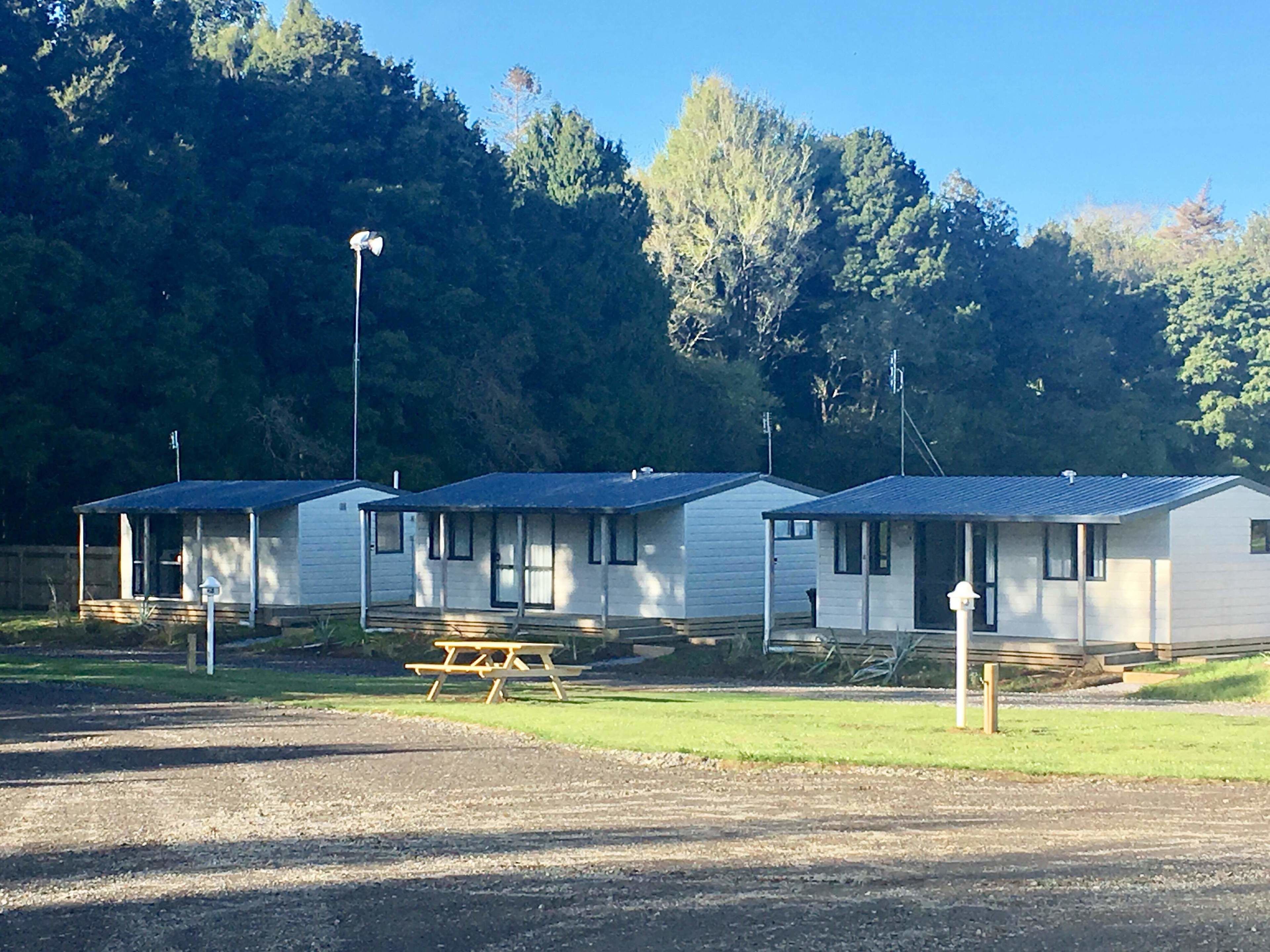 A row of mobile homes with attached porches, a picnic table, and a street lamp.