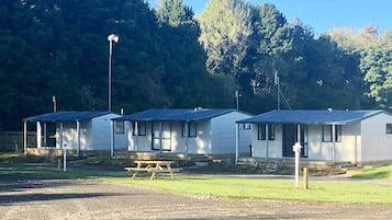 A row of mobile homes with attached porches, a picnic table, and a street lamp.
