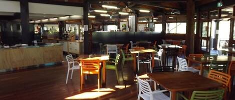A spacious indoor area with wooden flooring and a variety of seating arrangements including tables and chairs.
