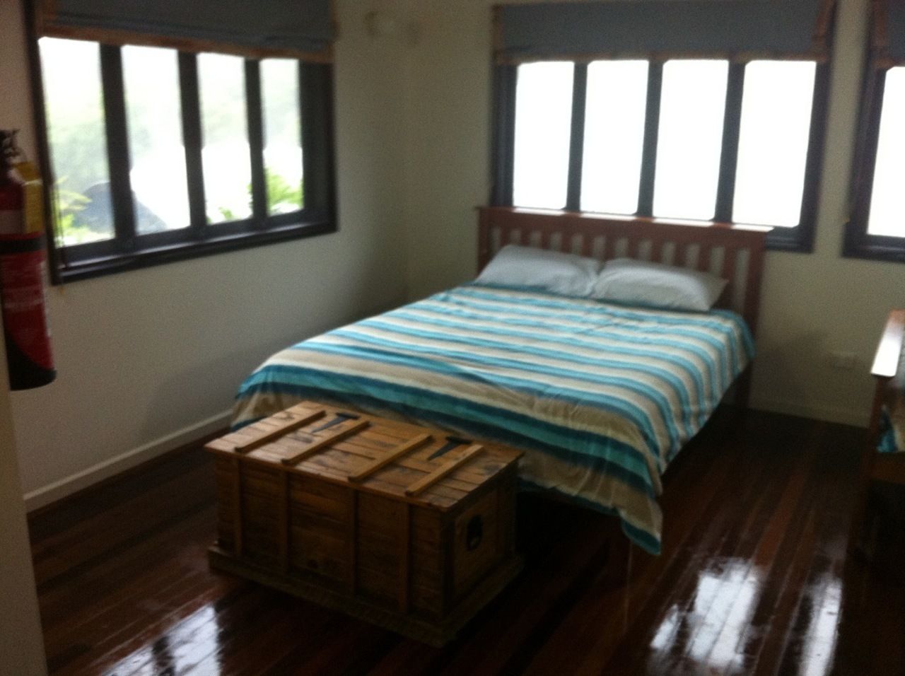 A bedroom with a wooden bed, striped bedding, and a wooden chest of drawers.