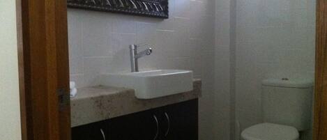 Une petite salle de bain avec un lavabo blanc, un miroir au-dessus et des toilettes.