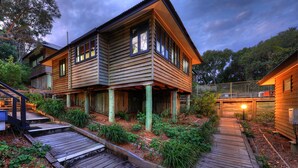 A two-story wooden house with a deck and a small garden area. - Fraser Island Retreat (K'gari (Fraser Island))
