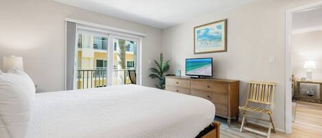 A bedroom with a large bed, a TV, a wooden chair, and a dresser.