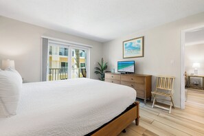 A bedroom with a large bed, a TV, a wooden chair, and a dresser. - Palm Bay Club by Beachside Management (Siesta Key)