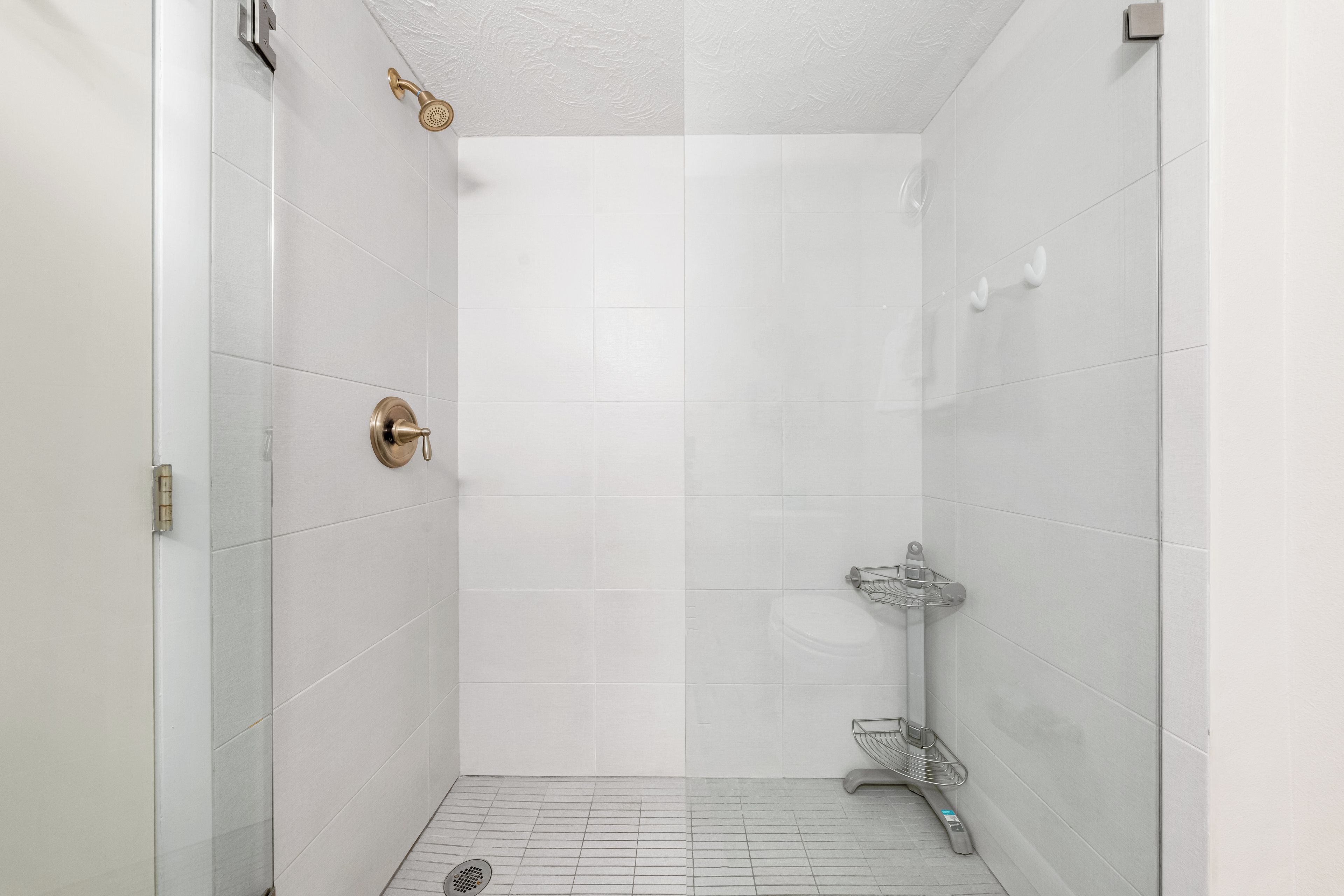 A modern bathroom with white tiles, a glass shower enclosure, and a metal towel rack.