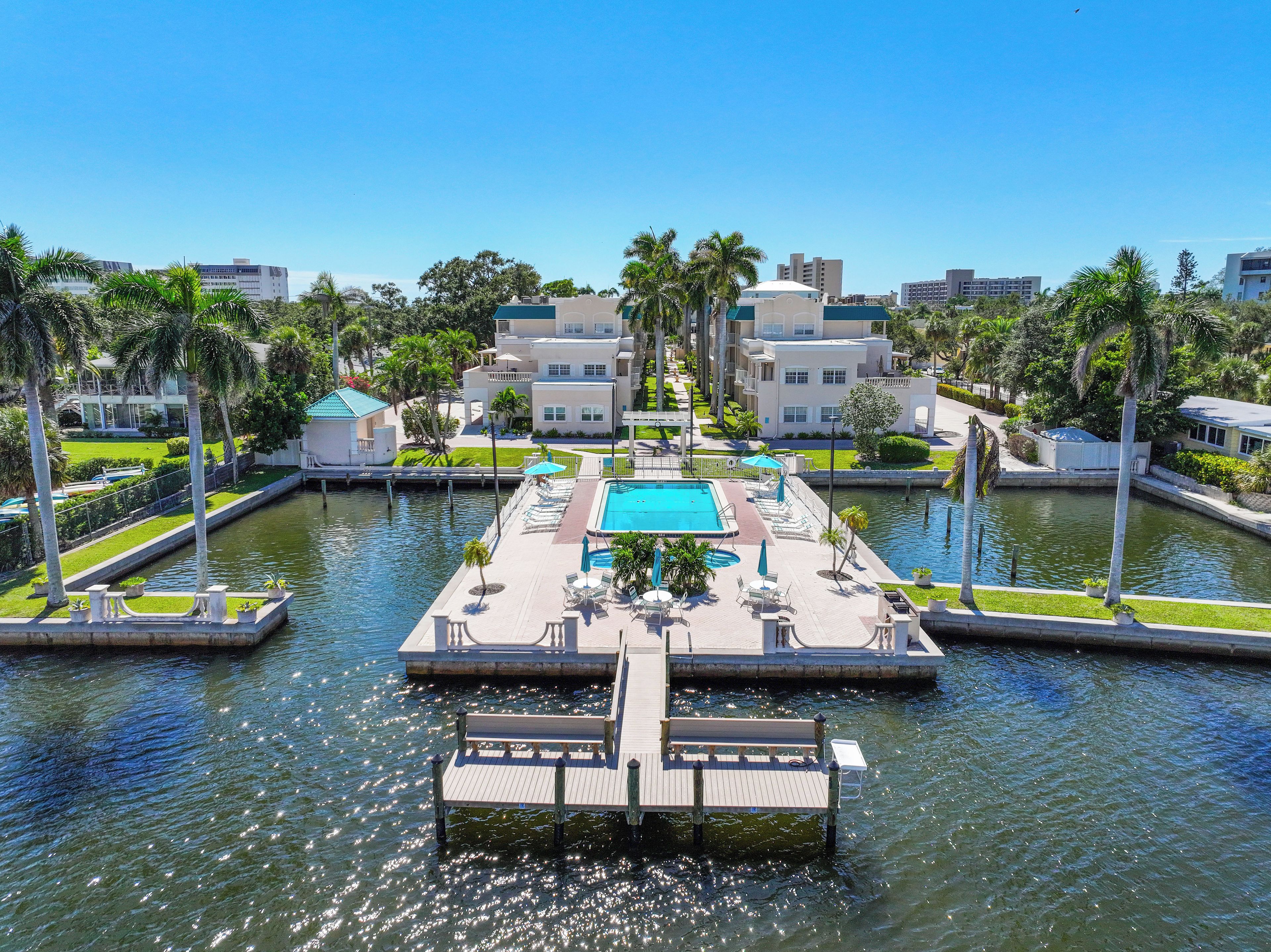 A marina with a swimming pool, docked boats, and a clear blue sky.