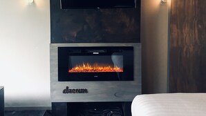 Una habitación moderna con chimenea, un televisor de pantalla plana montado encima y una alfombra estampada.