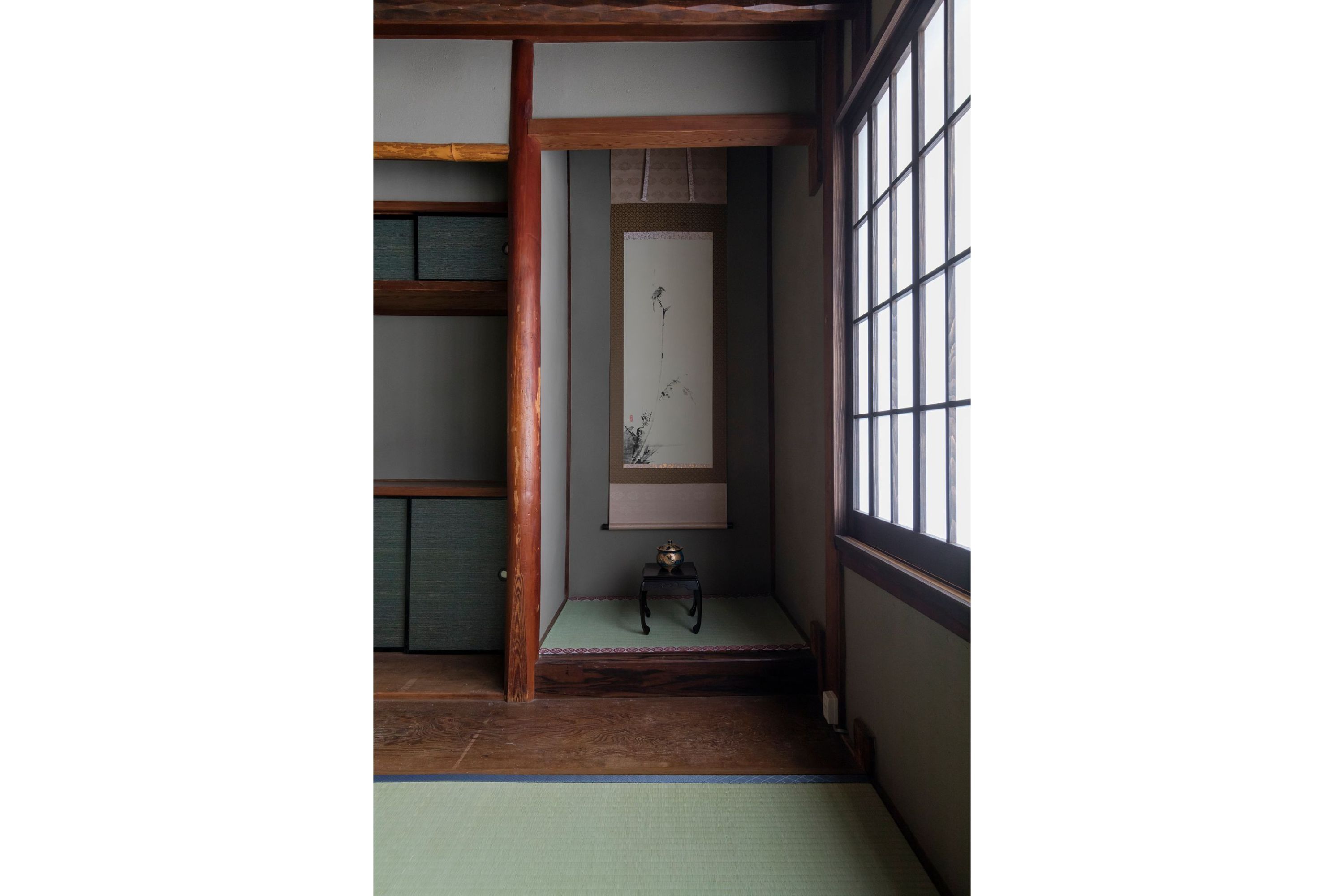 Een traditionele Japanse kamer met tatami vloerbedekking, een shoji schuifwand en een kleine tafel met een decoratief object.